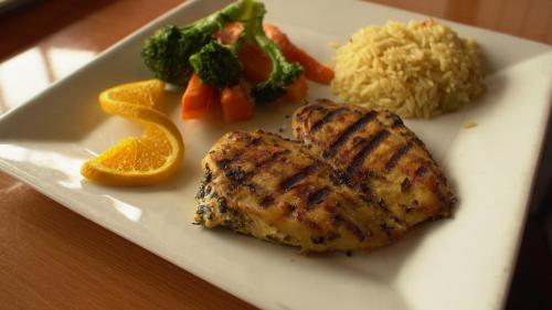 a plate of food with chicken and rice and vegetables at San Simeon Lodge in San Simeon