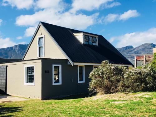 a house with a black roof with mountains in the background at Pringle @ 865 Jally in Pringle Bay
