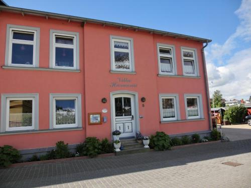 a red building with a white door on a street at Villa Harmonie in Lohme