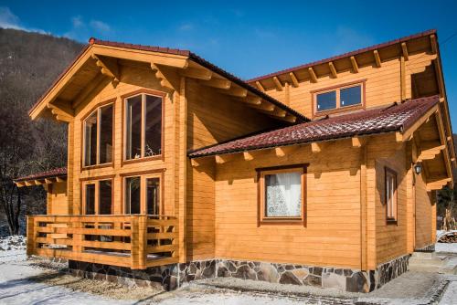 a log home in the winter with snow on the ground at Hargita Udvarhaz Zetevaralja in Sub Cetate