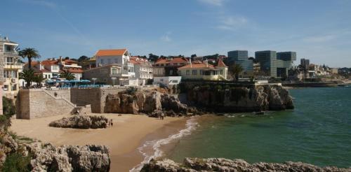 uma vista para uma praia com casas e a água em Suites Guest House em Cascais