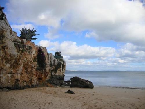 a beach with a rock wall and the ocean at Suites Guest House in Cascais