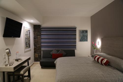 una camera con letto, scrivania e divano di Casa Massima Hotel a León