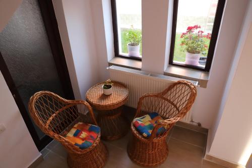 a room with three chairs and a table and two windows at Upstairs Residence in Târgu Jiu