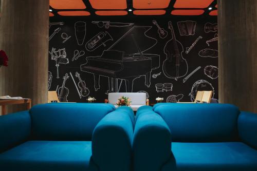 a blue couch in front of a wall with a piano at Hotel Del Fiol in Tatuí