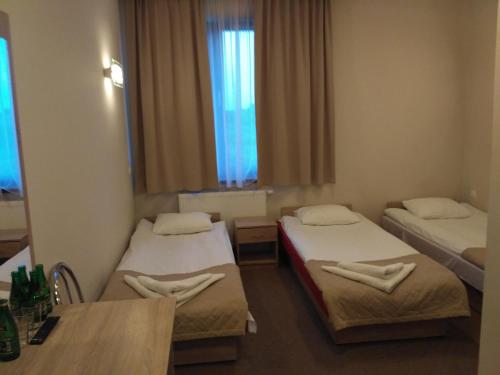 een kamer met 2 bedden, een tafel en een raam bij Hotel Nowostawy A2 MOP in Nowostawy Dolne