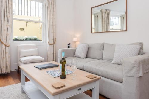 a living room with a couch and a table with a bottle of wine at Brunswick Patio Apartment by MyHolidayLet in Brighton & Hove