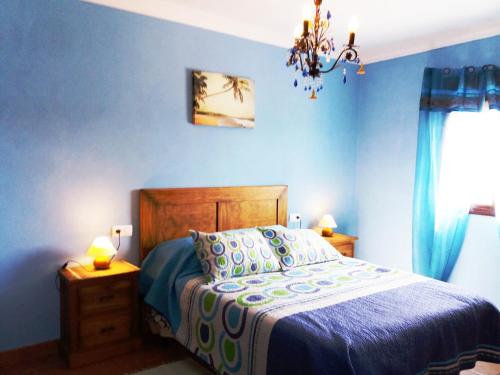 um quarto azul com uma cama e um lustre em Chalet Duna em El Palmar