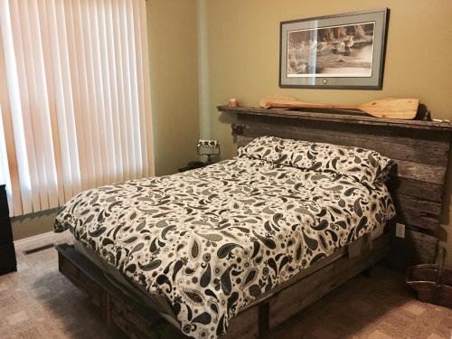 Schlafzimmer mit einem Bett mit einer schwarzen und weißen Bettdecke in der Unterkunft Pebble Springs BnB in Grand Beach