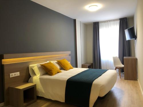Un dormitorio con una cama con almohadas amarillas y una ventana en Hotel Alda Estación Pontevedra, en Pontevedra