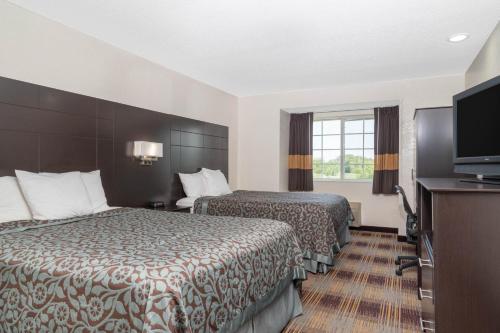 a hotel room with two beds and a flat screen tv at Days Inn by Wyndham Faribault in Faribault