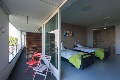 a bedroom with a bed and two chairs on a balcony at Hotel Middelpunt - Gratis Parking - Ontbijt inbegrepen! in Middelkerke