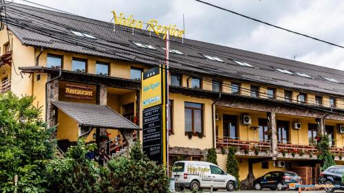 un edificio amarillo con un cartel delante en Valea Regilor Reghin en Reghin