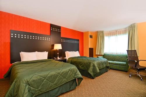 2 bedden in een hotelkamer met oranje muren bij Travelodge by Wyndham Absecon Atlantic City in Absecon