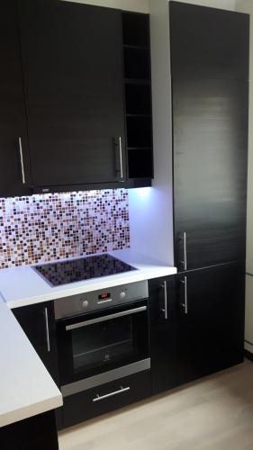 a kitchen with black cabinets and a stove top oven at Anne 80 Apartment in Tartu