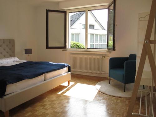 Hygge Apartments Bonn في بون: غرفة نوم بسرير وكرسي ونافذة