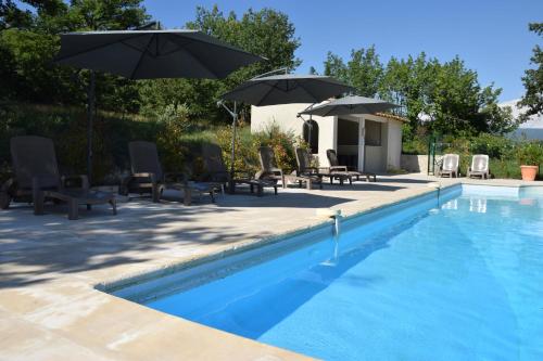 a swimming pool with chairs and umbrellas next to it at Moulin des Gypses Gîte Les Pierres Blanches, Ventoux in Mormoiron