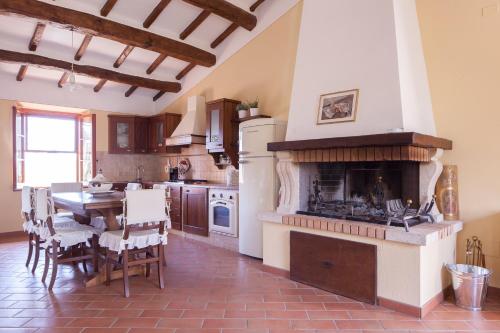 cocina con chimenea, mesa y sillas en Podere Villa Rosa en Torrita di Siena