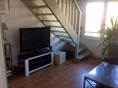 un soggiorno con TV a schermo piatto e scala di Appartement Vue Mer Benerville-sur-mer a Bénerville-sur-Mer