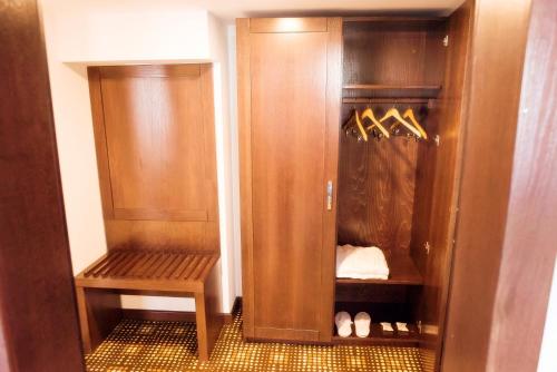 a closet with wooden cabinets and a bench in it at Hotel Bucovina in Suceava