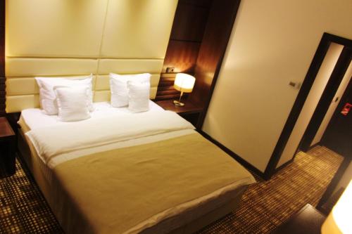 a hotel room with a bed with white sheets and pillows at Hotel Bucovina in Suceava