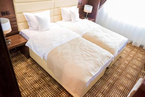 two beds in a hotel room with white sheets and pillows at Hotel Bucovina in Suceava