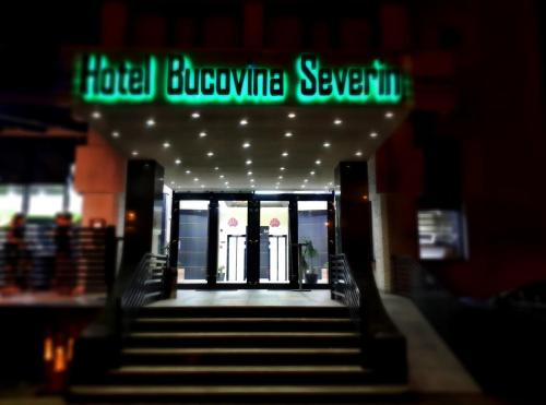 a stairway leading to a hotel lobby with a neon sign at Hotel Bucovina in Suceava