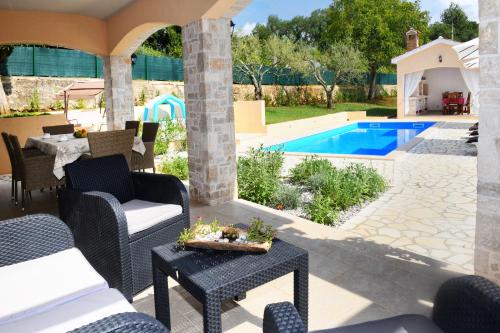 a patio with chairs and a table and a swimming pool at Villa Emilia in Vižinada