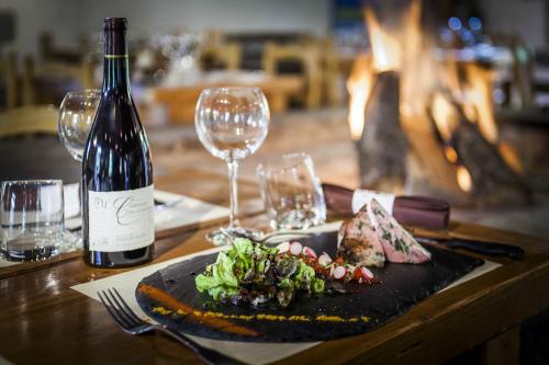 a table with a plate of food and a bottle of wine at Aux 500 Diables Eco Lodge - Hotel in Chambon-sur-Lac