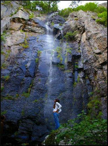 a woman standing in front of a waterfall at Aux 500 Diables Eco Lodge - Hotel in Chambon-sur-Lac