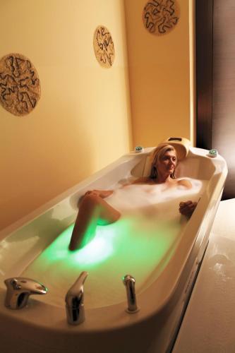 a woman laying in a bath tub with green light at Grand Hotel Donat Superior & Wellness Center in Rogaška Slatina