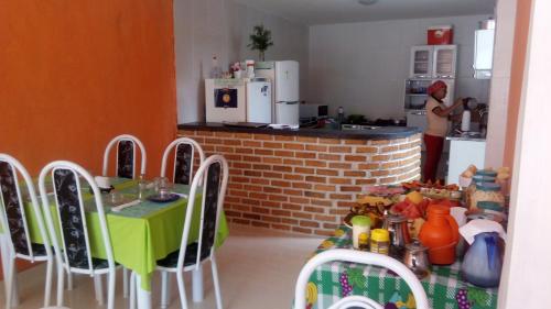 a woman in a kitchen with a table and chairs at Pousada Casa da Neuzita in Lençóis