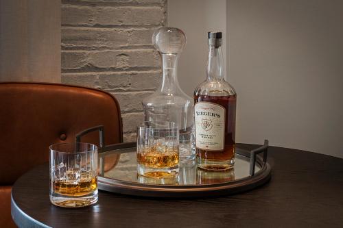 a bottle of whiskey and two glasses on a tray at Crossroads Hotel in Kansas City