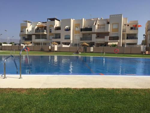 a swimming pool in front of a large apartment building at Playas de cabo in Retamar