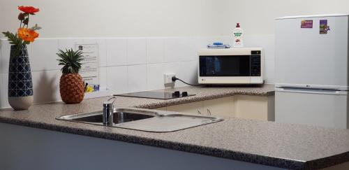 a kitchen counter with a sink and a microwave at Reef Palms in Cairns