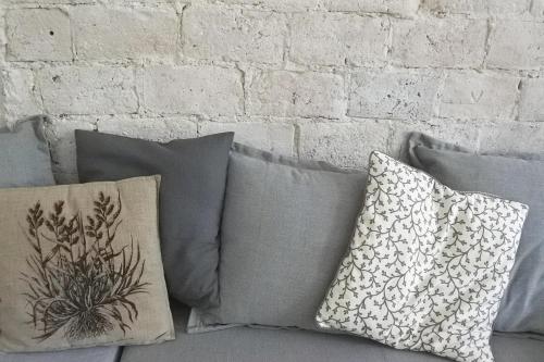 a bunch of pillows on a couch against a brick wall at APARTMÁN V ZAHRADĚ PRAHA TROJA - APARTMENT IN THE GARDEN PRAGUE Troja in Prague