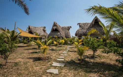 a row of cottages on the beach with palm trees at Swell in El Paredón Buena Vista