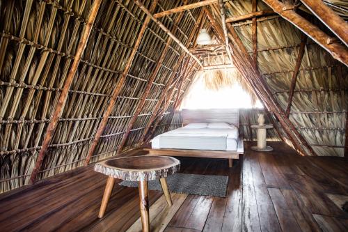 a room with a bed and a stool in a straw hut at Swell in El Paredón Buena Vista
