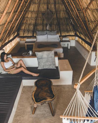 a woman sitting on a bed in a hut at Swell in El Paredón Buena Vista