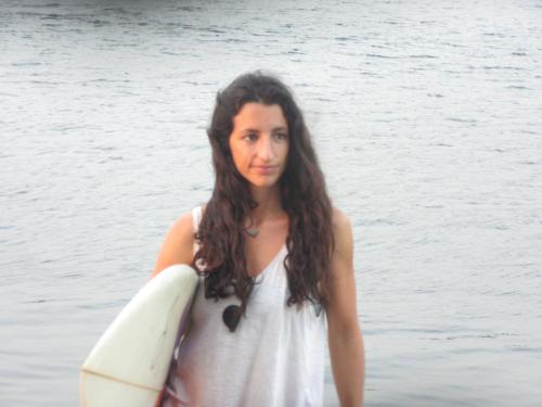 a woman standing in the water holding a surfboard at Swell in El Paredón Buena Vista