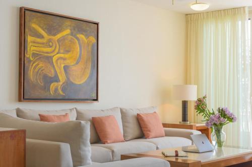 a living room with a couch and a painting on the wall at Grand Miramar All Luxury Suites & Residences in Puerto Vallarta