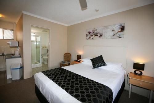 a hotel room with a large bed and a bathroom at Bella Villa Motor Inn in Forster