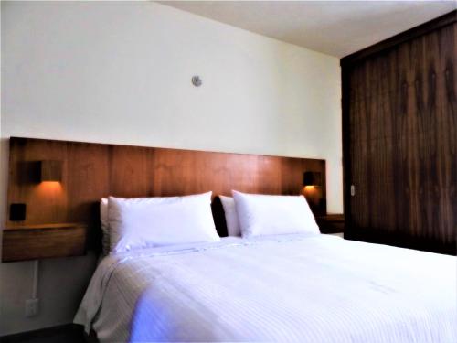 a bedroom with a large white bed with a wooden headboard at Villas La Ceiba in Playa del Carmen