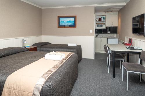 a hotel room with two beds and a table and a kitchen at Te Anau Top 10 Holiday Park and Motels in Te Anau