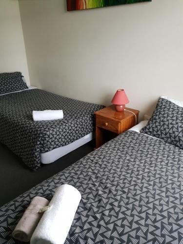 a room with two beds and a table with a lamp at Horse and Jockey Inn in Matamata