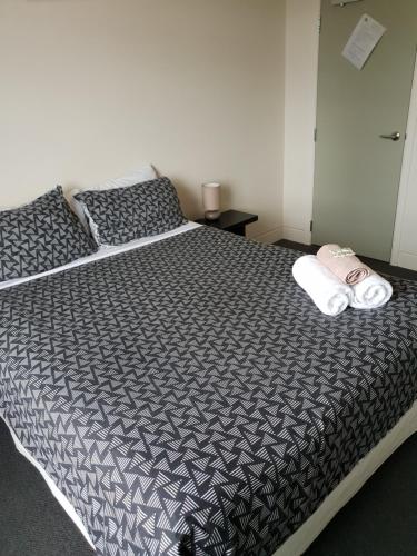 a bedroom with a bed with a black and white comforter at Horse and Jockey Inn in Matamata