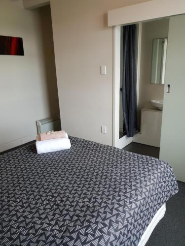 a bedroom with a bed with a black and white blanket at Horse and Jockey Inn in Matamata