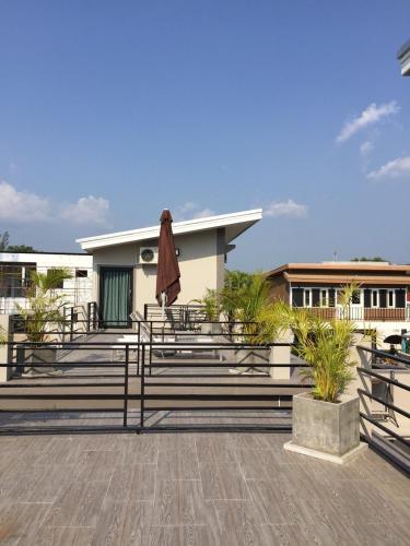 a patio with a umbrella and benches and a building at Baan Fran Sim Da in Bang Tao Beach