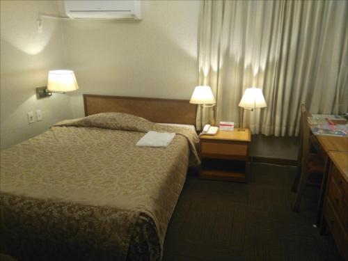 a hotel room with a bed and two lamps at Sunrise Hotel Okinawa-どこか懐かしいレトロな雰囲気の宿 in Okinawa City