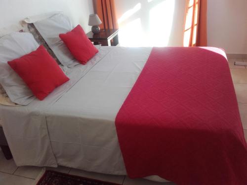 Una cama grande con almohadas rojas y blancas. en Nono, en Bouillante
